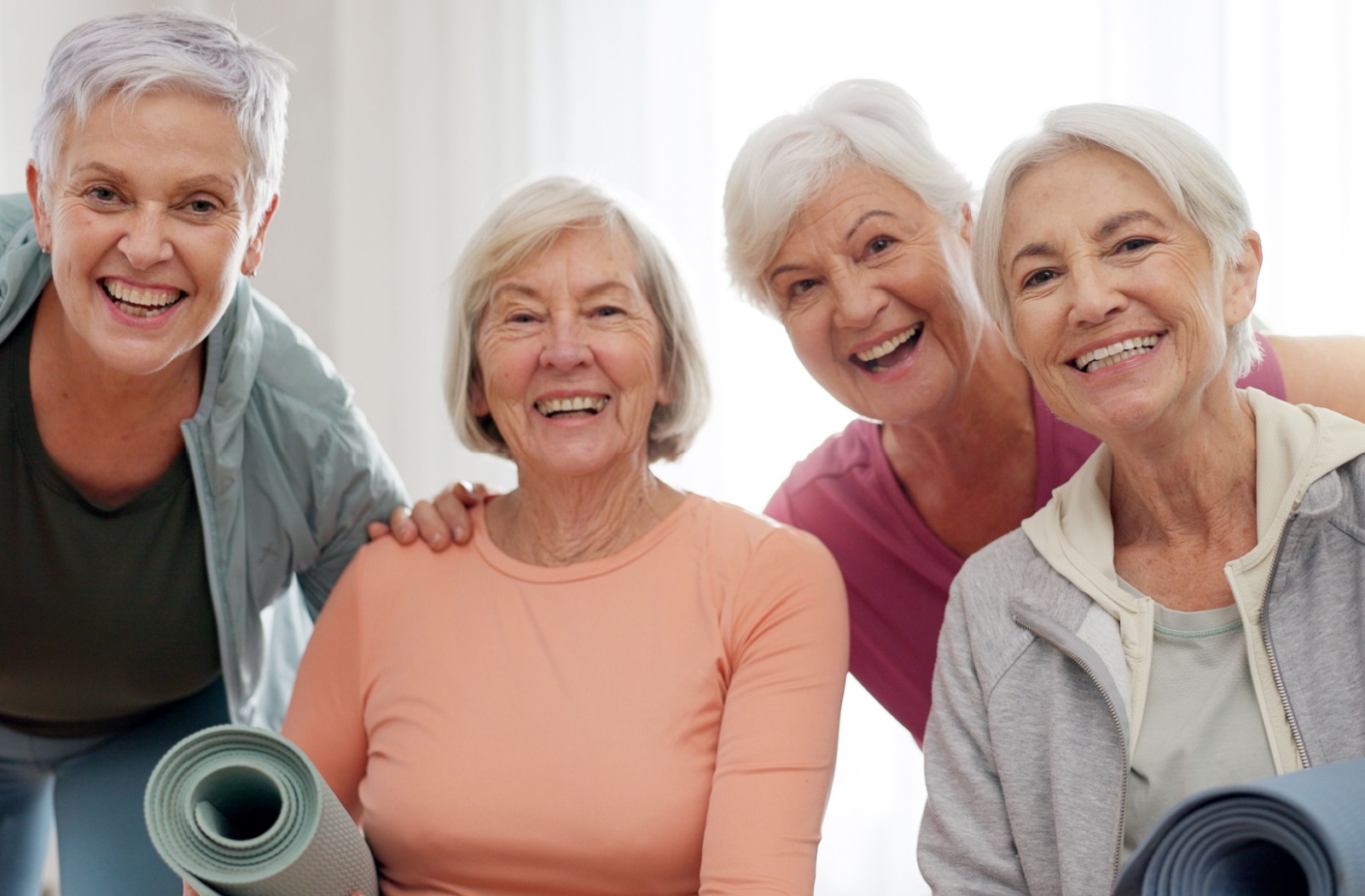 A smiling group of 4 older adults after an exercise class to help them stay fit.