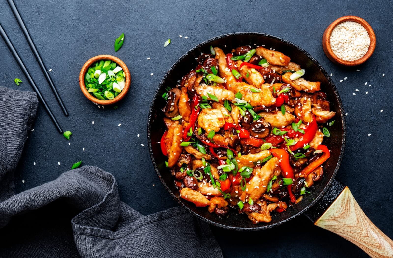 A flattering top-down view of a pan full of cooked chicken stir-fry, with peppers and mushrooms for extra nutrients