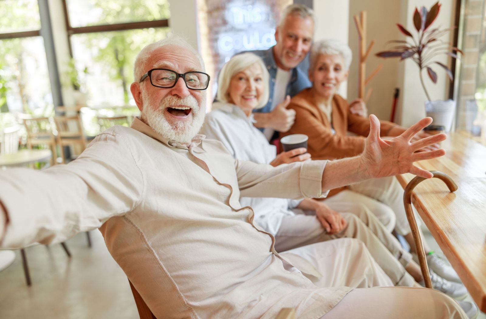 A grorup of 4 older adults laugh while sitting together in a common area of a senior living community