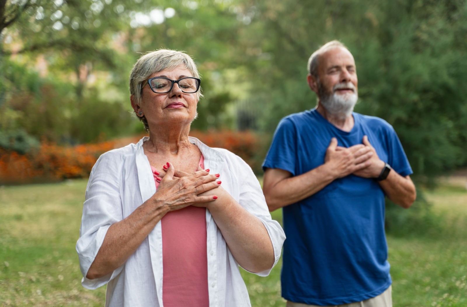Two seniors meditate in a public park on a warm summer day.