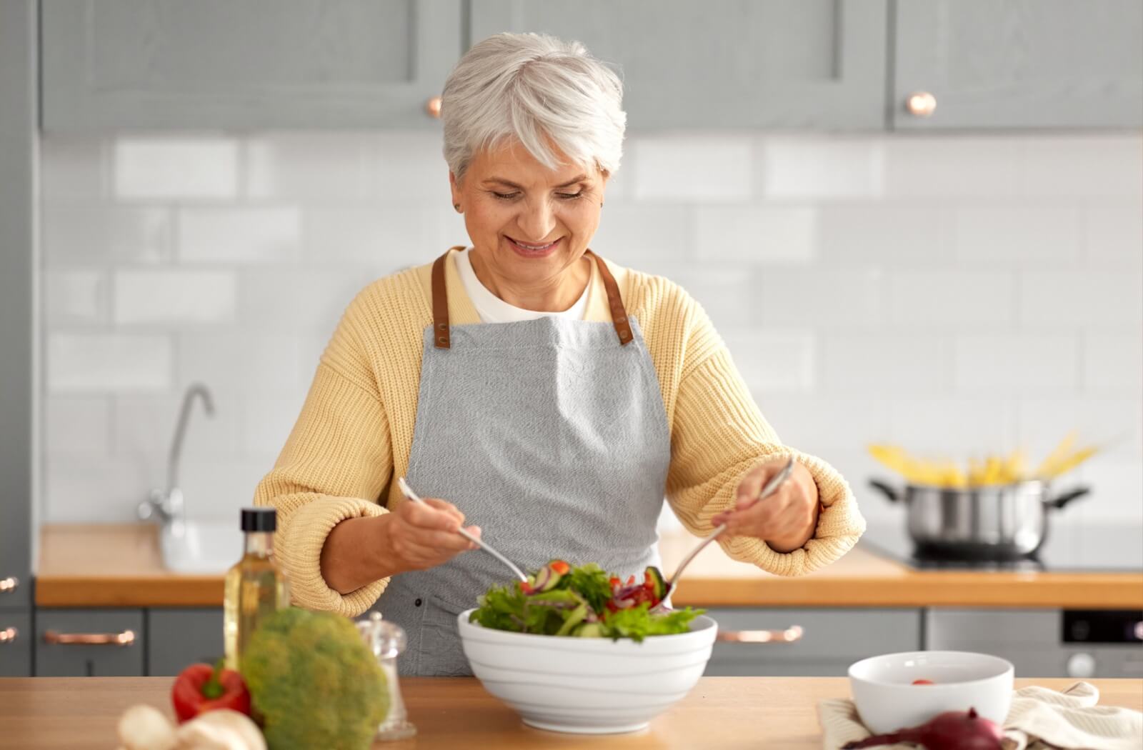 An older woman with silver-white hair expertly tosses her salad.