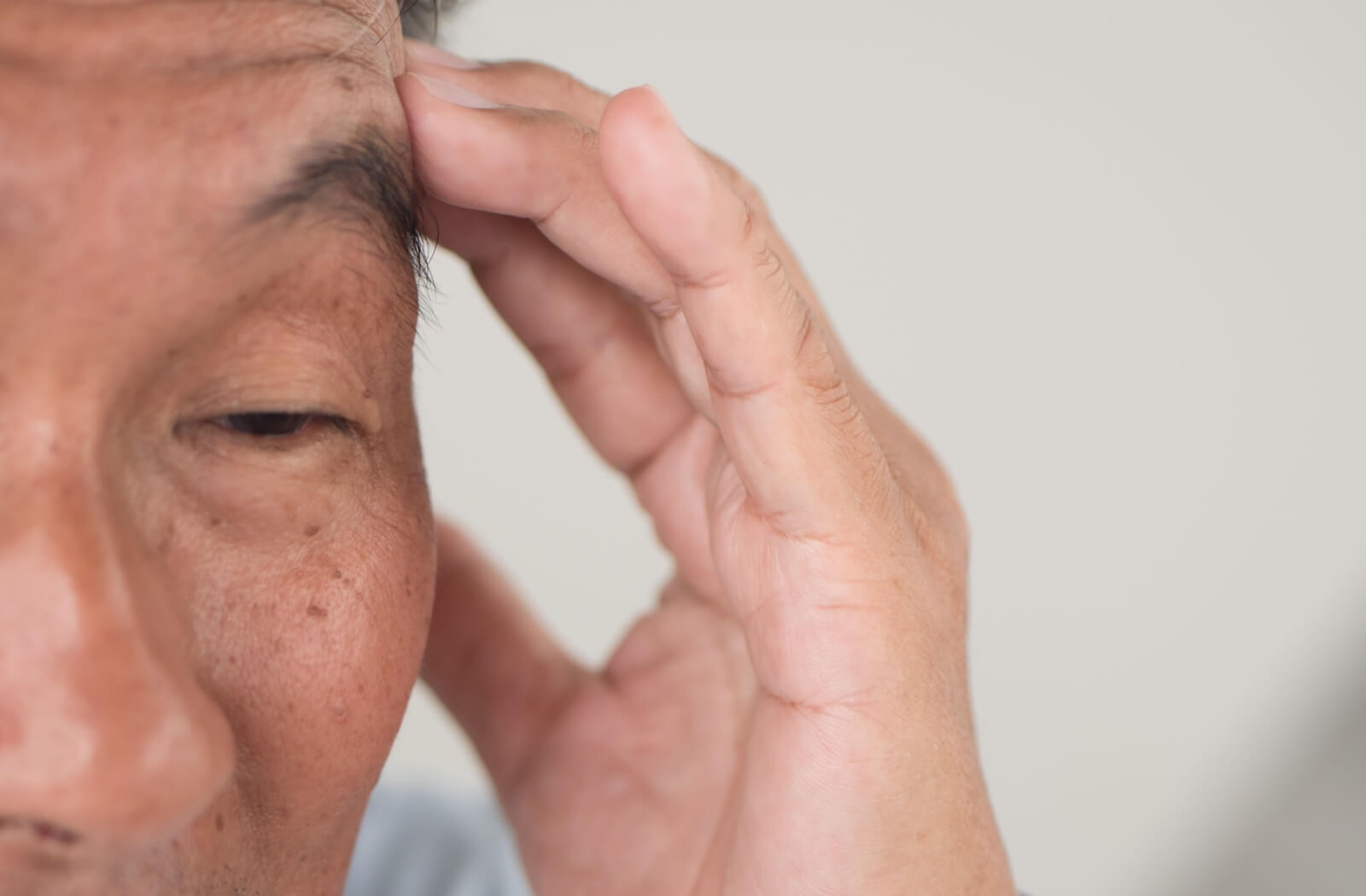 An older man touching his head trying to recollect his memory