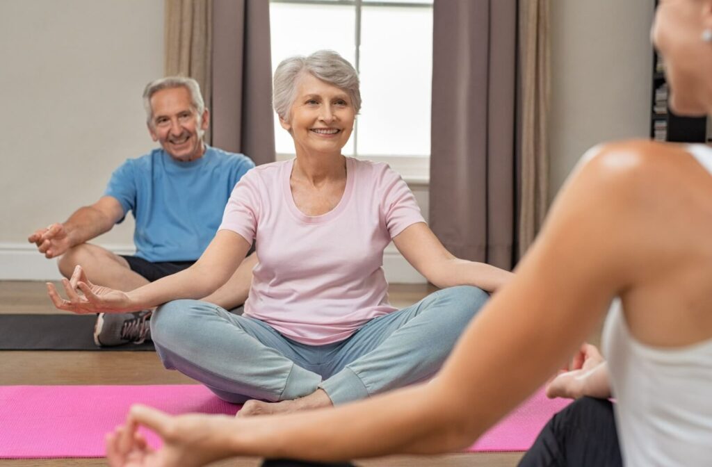 A group of older adults practicing yoga and sitting on yoga mats
