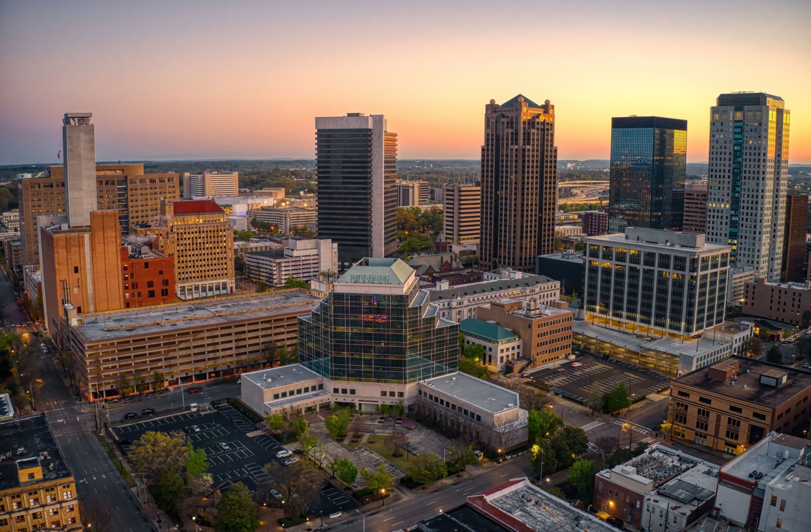 An aerial view looking at the downtown center of Birmingham, Alabama as the sun sets in the background.