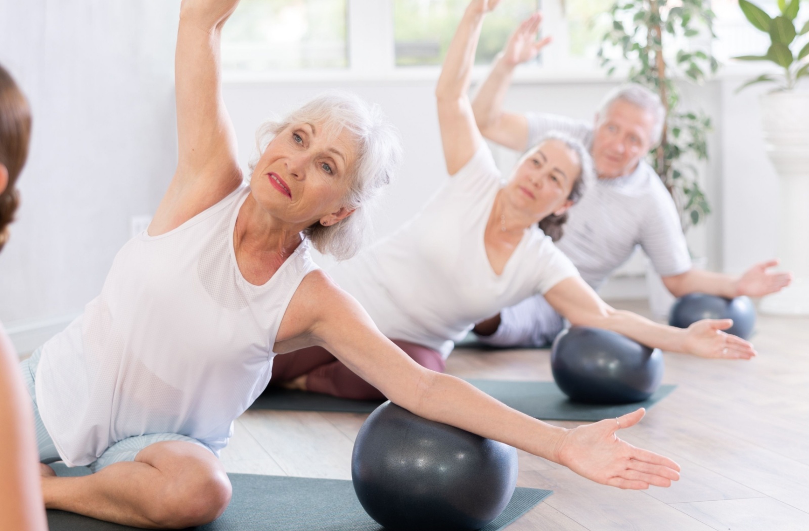 A group of older adults in senior living stretching during a yoga class for fitness.